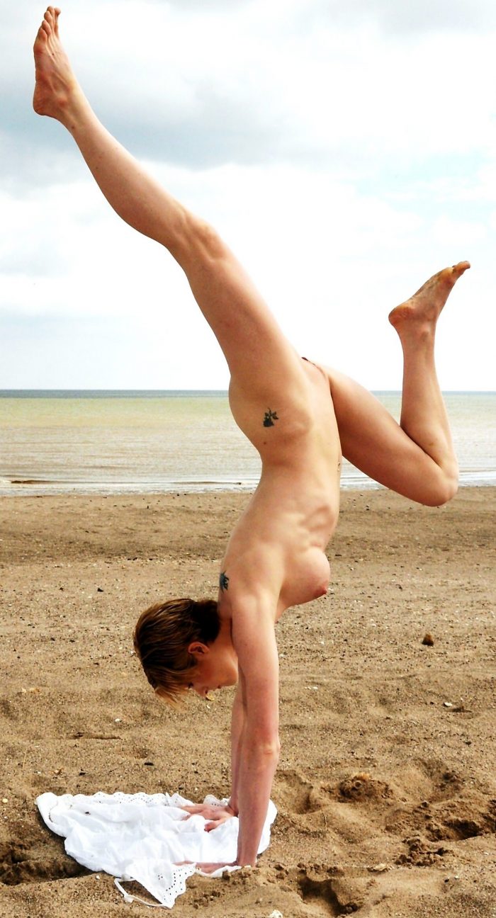 Flexible tattooed girl naked on the beach